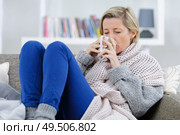 blonde sick woman laying on the couch with mug. Стоковое фото, агентство Ingram Publishing / Фотобанк Лори