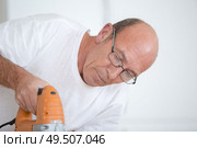 man cutting wood plank using electric jig saw. Стоковое фото, агентство Ingram Publishing / Фотобанк Лори