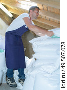 a worker moving white sacks. Стоковое фото, агентство Ingram Publishing / Фотобанк Лори