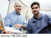 portrait of male apprentice with supervisor pointing at laptop. Стоковое фото, агентство Ingram Publishing / Фотобанк Лори
