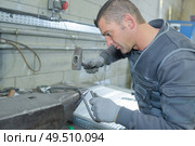 worker in factory with hammer on work bench. Стоковое фото, агентство Ingram Publishing / Фотобанк Лори