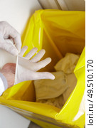 medic removing glove into bin with yellow liner. Стоковое фото, агентство Ingram Publishing / Фотобанк Лори