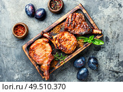 Spicy meat grilled spare ribs on wooden cutting board. Fried meat with plums. Стоковое фото, агентство Ingram Publishing / Фотобанк Лори