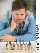 young man considering his next chess move. Стоковое фото, агентство Ingram Publishing / Фотобанк Лори