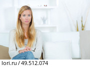 sad young woman sitting by sofa at home. Стоковое фото, агентство Ingram Publishing / Фотобанк Лори