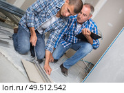 apprentice learning to cut tiles. Стоковое фото, агентство Ingram Publishing / Фотобанк Лори