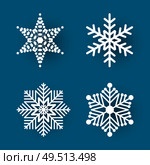 Christmas paper cut, four different white snowflakes on blue background. Decoration for winter holiday. Handmade small postcard vector illustration. Christmas Paper Cut Four White Snowflakes Vector. Стоковая иллюстрация, агентство Ingram Publishing / Фотобанк Лори
