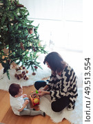 Mother and baby decorating and playing around the Christmas Tree. Стоковое фото, агентство Ingram Publishing / Фотобанк Лори