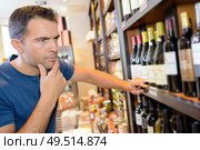 a customer reading a wine label. Стоковое фото, агентство Ingram Publishing / Фотобанк Лори