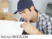 happy man screwing screws into furniture fittings. Стоковое фото, агентство Ingram Publishing / Фотобанк Лори