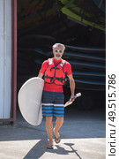 man holding stand up paddle board walking towards the water. Стоковое фото, агентство Ingram Publishing / Фотобанк Лори