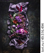 Beautiful purple fruit, vegetables and flowers composing on purple color tablecloth on dark background.Top view. Flat lay. Стоковое фото, агентство Ingram Publishing / Фотобанк Лори