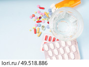 Coloful pills with glass of clear water close up over blue background with copy space. Medical pharmacy concept. Pile of pills. Стоковое фото, агентство Ingram Publishing / Фотобанк Лори
