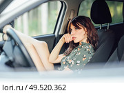 Thoughtful woman resting in a white car pulling her feet out the window. Female wearing flowered shirt and shorts.. Young woman resting in a white car pulling her feet out the window. Стоковое фото, агентство Ingram Publishing / Фотобанк Лори