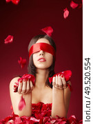 Charming girls blindfold with falling petals of roses on a red background. Стоковое фото, агентство Ingram Publishing / Фотобанк Лори