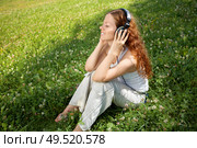 The girl sits on a meadow and listens to music in ear-phones. Стоковое фото, агентство Ingram Publishing / Фотобанк Лори