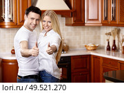 The young couple shows thumbs upwards on kitchen. Стоковое фото, агентство Ingram Publishing / Фотобанк Лори