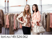 Two girls near to regiments with clothes. Стоковое фото, агентство Ingram Publishing / Фотобанк Лори
