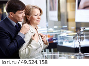 The man of middle age helps the woman to put on a jewel. Стоковое фото, агентство Ingram Publishing / Фотобанк Лори