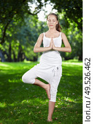 Attractive young woman practices yoga in the park. Стоковое фото, агентство Ingram Publishing / Фотобанк Лори