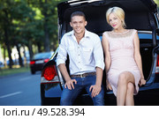 Young couple sitting on the trunk of a car. Стоковое фото, агентство Ingram Publishing / Фотобанк Лори
