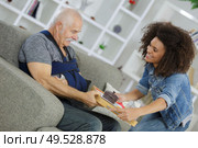 young girl volunteer is giving food to senior injured man. Стоковое фото, агентство Ingram Publishing / Фотобанк Лори