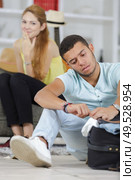 girlfriend laughing at man struggling to close suitcase. Стоковое фото, агентство Ingram Publishing / Фотобанк Лори
