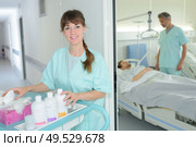 portrait of auxiliary nurse with trolley outside of patients room. Стоковое фото, агентство Ingram Publishing / Фотобанк Лори