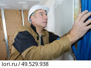 Tradesman fitting conduit into wall cavity. Стоковое фото, агентство Ingram Publishing / Фотобанк Лори