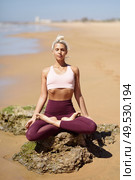 Caucasian woman practicing yoga at seashore. Young female doing lotus pose in the beach in Cadiz, Andalusia, Spain.. Caucasian blonde woman practicing yoga in the beach. Стоковое фото, агентство Ingram Publishing / Фотобанк Лори