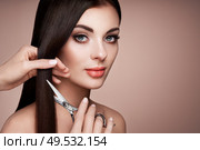 Portrait of beautiful young woman getting haircut. Brunette model. Hair salon, hairstylist. Care and beauty hair products. Perfect make-up. Стоковое фото, агентство Ingram Publishing / Фотобанк Лори