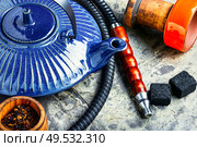 Details of tobacco hookah and teapot with tea.Egyptian smoking shisha and teakettle. Oriental hookah with kettle. Стоковое фото, агентство Ingram Publishing / Фотобанк Лори