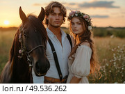 A man and a woman are posing in front of a horse in a field. Стоковое AI-изображение, AI-художник Ярославский Максим / Фотобанк Лори