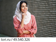 Happy Arab woman wearing hijab headscarf walking in the city center. Muslim female in urban background. Young Muslim woman wearing hijab headscarf walking in the city center. Стоковое фото, агентство Ingram Publishing / Фотобанк Лори