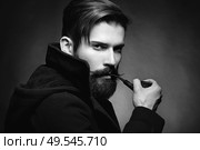 Brutal man with a beard and mustache Smoking a pipe. Close-up image of serious bearded man on dark background. Black and white photography. Стоковое фото, агентство Ingram Publishing / Фотобанк Лори