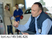 mechanic with clipboard customer waiting in background. Стоковое фото, агентство Ingram Publishing / Фотобанк Лори