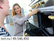 Lady pointing to controls on range cooker. Стоковое фото, агентство Ingram Publishing / Фотобанк Лори