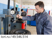 mechanic balancing wheel with machine at garage. Стоковое фото, агентство Ingram Publishing / Фотобанк Лори