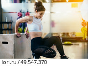 Athletic woman doing triceps push-ups with a wooden box at the gym.. Athletic woman doing triceps push-ups at the gym. Стоковое фото, агентство Ingram Publishing / Фотобанк Лори
