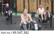 Determined young girl training with rowing machine in sports hall during workout. Стоковое видео, видеограф Яков Филимонов / Фотобанк Лори