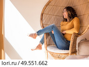 Optimistic woman sitting in a confortable rattan chair at home. Стоковое фото, агентство Ingram Publishing / Фотобанк Лори