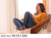 Optimistic woman sitting in a confortable rattan chair at home. Стоковое фото, агентство Ingram Publishing / Фотобанк Лори