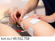 Physiotherapist applying electro stimulation in physical therapy to a young woman.. Electro stimulation in physical therapy to a young woman. Стоковое фото, агентство Ingram Publishing / Фотобанк Лори
