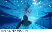 Swimmer dives into a blue pool during a training session for an upcoming competition in the morning light. Стоковое AI-изображение, AI-художник Сергей Толмачёв / Фотобанк Лори