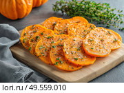 Cutting Fresh Pumpkins on Board. Baked pumpkin. Sliced raw Cucurbita maxima and spices for preparing soup, warm salad, fall dish. Thanksgiving food. Roasted vegetable in olive oil salt pepper, herbs. Стоковое AI-изображение, AI-художник Марина Демидюк / Фотобанк Лори