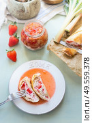Tasty strawberry rhubarb strudel cake with sweet berries sauce in plate with fork on light table background with ingredients. Top view. Organic home baking. Seasonal eating. Стоковое фото, агентство Ingram Publishing / Фотобанк Лори