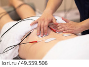 Physiotherapist applying electro stimulation in physical therapy to a young woman.. Electro stimulation in physical therapy to a young woman. Стоковое фото, агентство Ingram Publishing / Фотобанк Лори