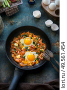 Tasty fried egg with tomatoes paprika sauce in fried pan with forks. Healthy breakfast. Shakshuka original on rustic background . Top view. Стоковое фото, агентство Ingram Publishing / Фотобанк Лори