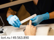 Aesthetician doing the manicure, filing the nails with a file to his client in a beauty center. Business and beauty concepts. Aesthetician doing the manicure, filing the nails with a file to his client in a beauty center. Стоковое фото, агентство Ingram Publishing / Фотобанк Лори