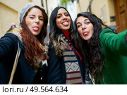 Multiethnic group of woman taking a selfie photo sticking out their tongues outdoors. Group of woman taking a selfie photo sticking out their tongues. Стоковое фото, агентство Ingram Publishing / Фотобанк Лори